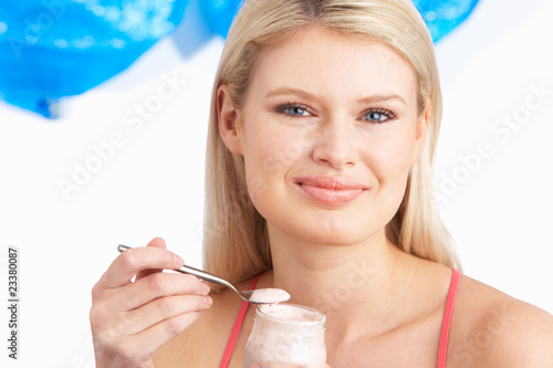 Photo: Young Woman Eating Yoghurt In Studio Young Woman Eating Yoghurt In Studio