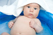 Baby mit Handtuch über dem Kopf im Planschbecken