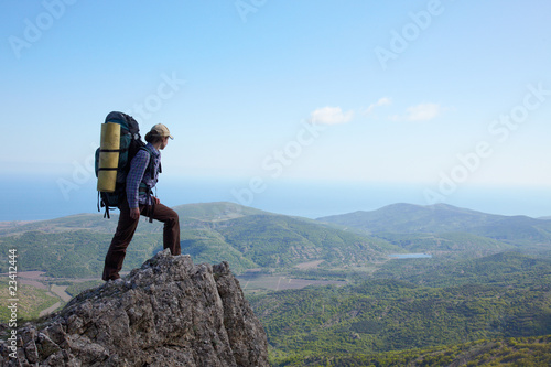 Photo: Backpacker girl standing on a high rock Backpacker girl standing on a high rock