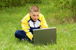 The boy with the computer on a grass