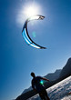 An adult male waits to collect a kitesurfer's kite.