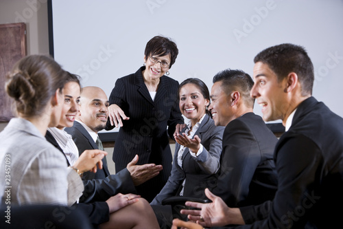 Photo: Diverse businesspeople conversing, woman at front Diverse businesspeople conversing, woman at front