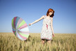 red-haired girl with umbrella at wheat field