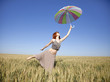 red-haired girl with umbrella at wheat field