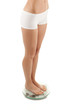 Slim woman standing on weight on white background