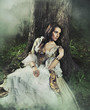 Gorgeous brunette beauty in a old-fashioned dress in a forest