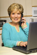 Woman talks on phone while working on laptop Woman talks on phone while working on laptop