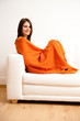 Foto: junge frau entspannt sich mit orangener decke auf sofa junge frau entspannt sich mit orangener decke auf sofa