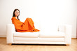 Foto: junge frau entspannt sich mit orangener decke auf sofa junge frau entspannt sich mit orangener decke auf sofa