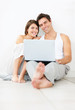 Young couple using laptop while sitting on the floor