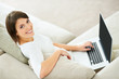 Photo: Young woman using laptop and looking at you Young woman using laptop and looking at you