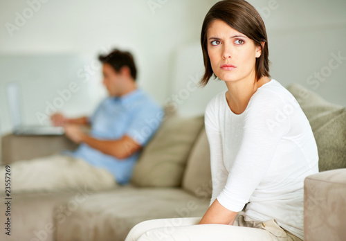 Foto: Upset young woman sitting with her husband in background Upset young woman sitting with her husband in background