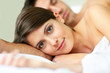 Young woman relaxing with her husband on bed