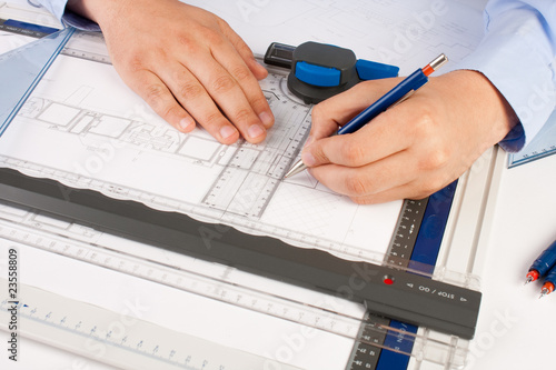 Photo: Architect working on architectural plans in the office Architect working on architectural plans in the office