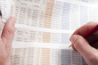 Man working out figures from newspaper holding pencil