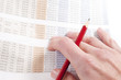 Man working out figures from newspaper holding pencil