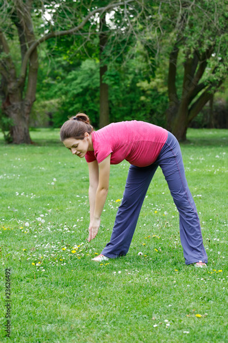 Photo: Beautiful pregnant woman exercising in the park Beautiful pregnant woman exercising in the park