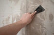 Hand mit Spachtel und Wand