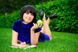 Young beautiful woman lays on green field with apple and book