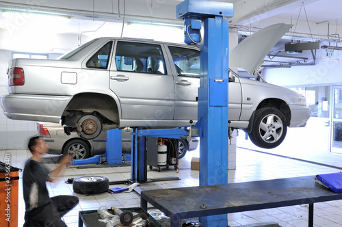 Photo: Auto mechanic changing tire under the car. Auto mechanic changing tire under the car.