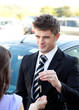 Young salesman giving car's key