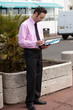 Businessman working outside, looking down at clipboard or folder