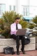 Smart young businessman sitting outside with laptop
