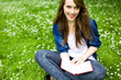 Young woman sitting with book on grass