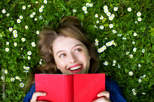 Foto: Woman lying on grass, reading book Woman lying on grass, reading book
