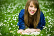 Woman lying on grass with book