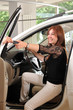 Car dealer giving keys of new car to happy red head customer.