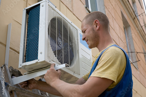 Foto: Young setup man installs the new air conditioner. Young setup man installs the new air conditioner.