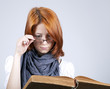 Young doubting fashion girl in glasses with old book