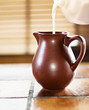 Milk pouring in a brown jug