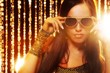Attractive woman in sunglasses over golden curtains