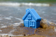 Toy plastic house on the sand washes wave Toy plastic house on the sand washes wave