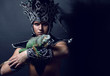 Young pagan priest in ritual suit with green iguana in his hands
