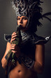 Young pagan priest in ritual suit with green iguana in his hands