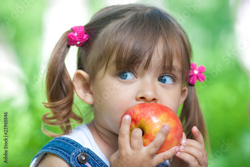 Photo: Little girl portrait eating red apple outdoor Little girl portrait eating red apple outdoor
