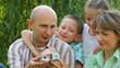 family sits in park and taking good look at toy house