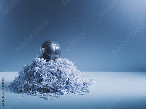 Foto: Metal globe on pile of shredded paper Metal globe on pile of shredded paper