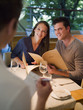 Waiter taking order from couple with menus at restaurant table