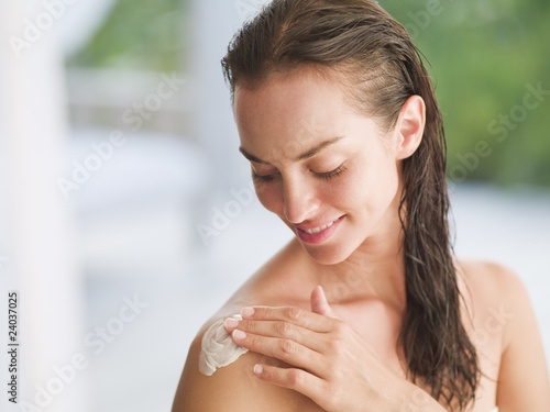 Photo: Woman applying lotion to shoulder Woman applying lotion to shoulder