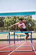 Runner jumping hurdles on track