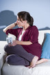 Pensive woman drinking coffee thinking on sofa