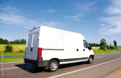 Foto: White delivery mini truck on highway over blue sky. White delivery mini truck on highway over blue sky.