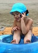 Foto: Boy having rest on beach, talks by mobile phone. Boy having rest on beach, talks by mobile phone.