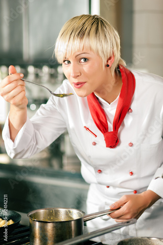 Foto: Köchin in Restaurantkücke schmeckt ab Köchin in Restaurantkücke schmeckt ab
