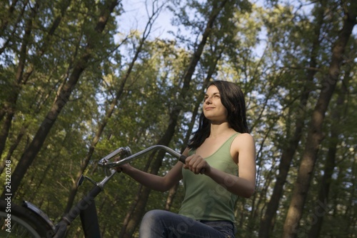 Photo: Young woman stands with bicycle in woodland Young woman stands with bicycle in woodland