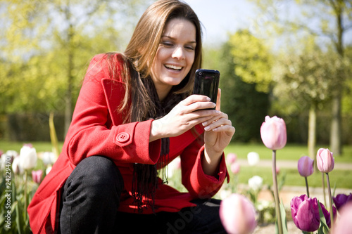 Photo: A young woman photographing flowers with her phone A young woman photographing flowers with her phone